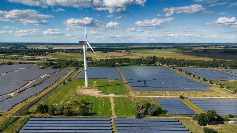 Eine Photovoltaik-Freiflächenanlage (Solarpark), betrieben von der Firma Enerparc. Zahlreiche Solarzellen im Solarkraftwerk wandeln Sonnenenergie in grünen Strom um. Im Solarpark gibt es eine Windkraftanlage. (Luftbild mit Drohne) Eine Photovoltaik-Freiflächenanlage (Solarpark), betrieben von der Firma Enerparc. Zahlreiche Solarzellen im Solarkraftwerk wandeln Sonnenenergie in grünen Strom um. Im Solarpark gibt es eine Windkraftanlage. (Luftbild mit Drohne)
